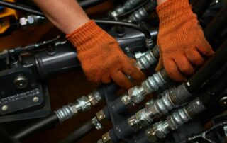 hands performing repairs on hydraulic hoses